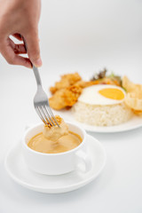 Buttermilk chicken rice with ingredients isolated on white with fried egg and salad. Chicken dumb into buttermilk sauce.