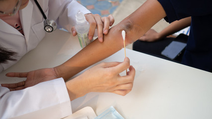Doctor is using cotton dressing a wound at a women arm.