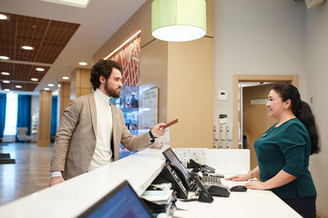 Fototapeta premium young friendly manager checking the guest in, registration concept. process. close up side view photo, man odering breakfast, lunch, booking a room.Reservation