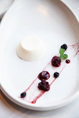 Panna cotta dessert with berries on a white plate