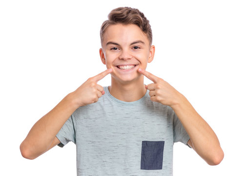 Portrait of teen boy showing his teeth. Child pointing with finger teeth and mouth. Caucasian young teenager, isolated on white background. Concept of good teeth care. Dental health concept.