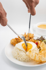 Buttermilk chicken rice with ingredients isolated on white with fried egg and salad. Fork and knife cut the fried egg.