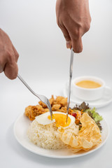 Buttermilk chicken rice with ingredients isolated on white with fried egg and salad. Fork and knife cut the fried egg.