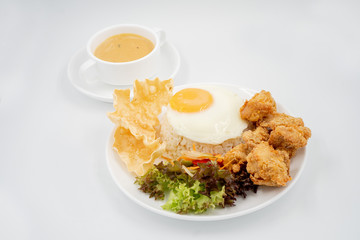 Buttermilk chicken rice with ingredients isolated on white with fried egg and salad.