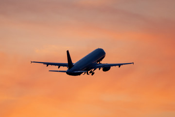 Fototapeta na wymiar Startendes Flugzeug fliegt dem Sonnenuntergang entgegen