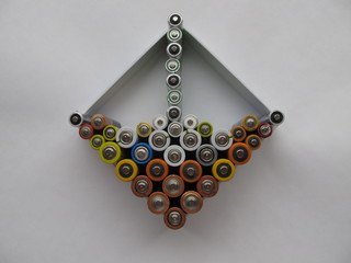 Used batteries in a white box are ready for the disposal, on a light background. Ecology concept.