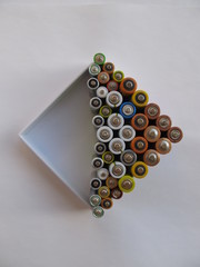 Used batteries in a white box are ready for the disposal, on a light background. Ecology concept.