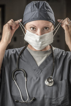 Female Doctor or Nurse with Stethoscope Putting On Protective Face Mask