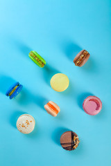 Different types of colorful sweet macaroons dessert on blue background