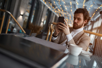 young handsome man working with smart phone, texting message, e-mail, chatting with girlfriend, close up photo