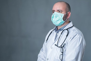 Male doctor with medical mask protection in soft grey background