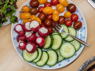 Plate with fresh vegetables: cucumber, radishes, tomatoes