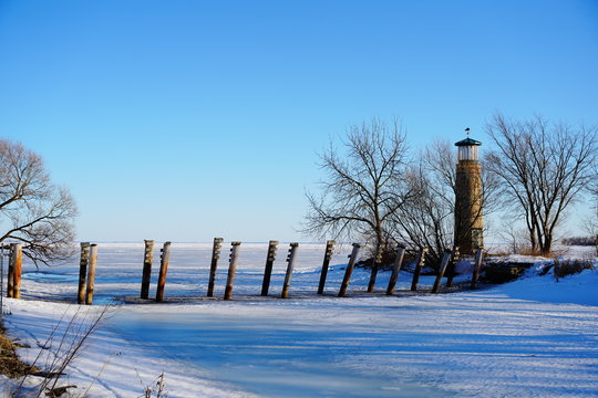 Old Vintage Historical Asylum Point Lighthouse Standing Off Of The Frozen Lake Winnebago Out In Oshkosh, Wisconsin During The Cold Winter Season.