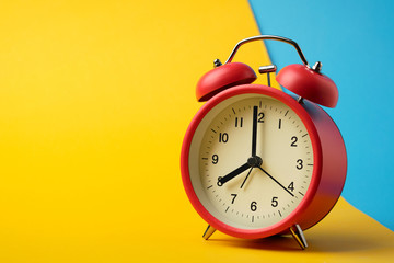 Red vinatge alarm clock show 8 o'clock with yellow and blue background.