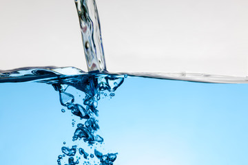 Pouring blue water splash and air bubbles isolated on white background