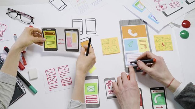 A team of UX creative designers  web application development for mobile phones. Engineering draw sketch of the user interface. 