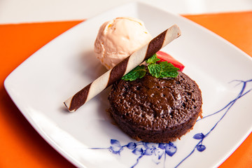 Homemade chocolate fondant, vanilla ice cream, chocolate wafer stick roll, strawberry and mint leaves
