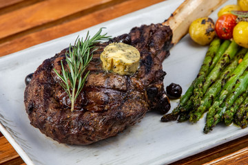 Thick juicy beef steak with green asparagus spears, tomato and baby young potatoes, rosemary and butter.