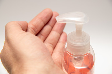 Clear pink hand sanitizer in a clear pump bottle isolated. Hand sanitizer is used for killing germs, bacteria and viruses, some of which can cause coronavirus COVID-19 H1N1 flu or swine flu.