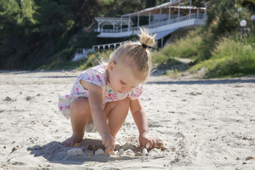 Cute toddler girl playing with sand on the beach