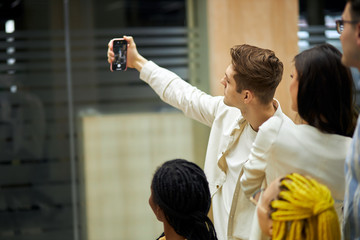 handsome blonde guy holding his mpbile phone, taking selfiew with his colleagues, close up photo. man testing his new camera, smart phone, checking the quality of camera