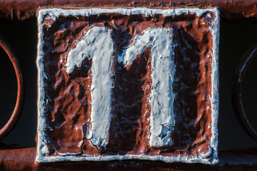 Old retro weathered cast iron plate with number 11 closeup