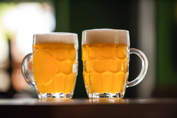 two mugs full of chopp, with chopp pilsen on a rustic table