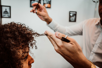 Beautiful latin woman with short curly brown hair getting a treat at the hairdresser. Latin hairdresser working her afro hair. Lifestyle. Close up