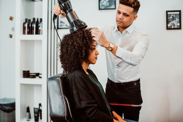 Beautiful latin woman with short curly brown hair getting a treat at the hairdresser. Latin...