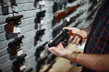 Man holds handgun in gun shop - obrazy, fototapety, plakaty