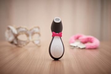 satisfyer pro penguin, the most famous dildo for women. with some handcuffs and a mask out of focus...