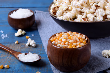 Fototapeta na wymiar Unpopped corn kernels for making popcorn in a wooden cup on blue table