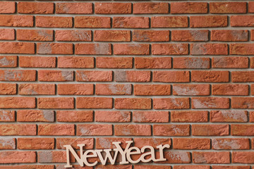 Fototapeta na wymiar Letters with the inscription New Year on the background of a brick red wall. Photography, concept.