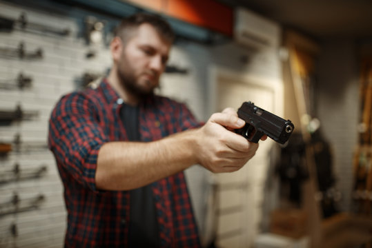 Man aims with two handguns in gun shop