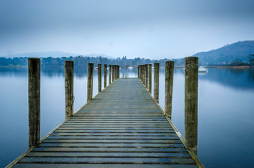 Fototapeta premium An evening view of one of the many jetties lining the shore of Lake Windermere showing a calm and misty water, 