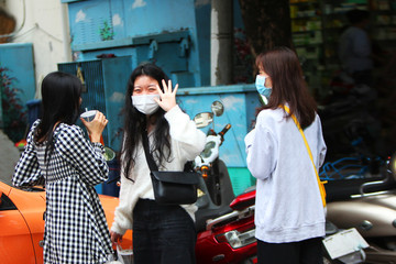 Young Chinese girls are standing on the street in gauze masks on their faces. The threat of a coronavirus epidemic in China. Copy space.