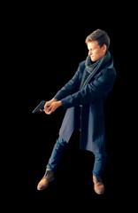 Side view of a young cop in a coat and scarf holding a gun in hands. Aim. Special operation. Isolated