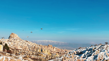 Pigeons are flying at Pigeon Valley in Cappadocia. Birds flying together with snowy volcanic landscape in Cappadocia, Turkey