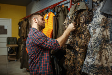 Man choosing uniform on showcase in gun shop