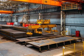 Overhead crane with electromagnetic beam grippers lifting steel sheets