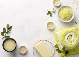 sea salt, scrub, solid soap and bath towels on a white stone background with candles. spa treatments background. flat lay, empty space for text