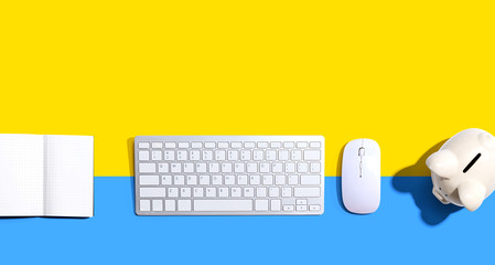 Computer keyboard with a piggy bank and a notebook - flat lay