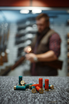 Ammo on counter, man loads a rifle on background