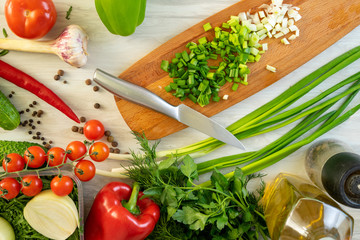 High Angle Still Life View of Knife and Wooden Cutting Board Surrounded by Fresh Herbs and...