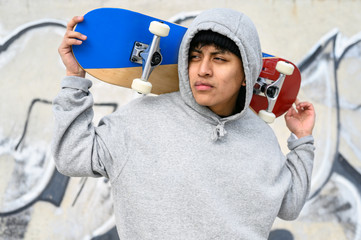 Young latin skater man posing with skateboard at skate park .