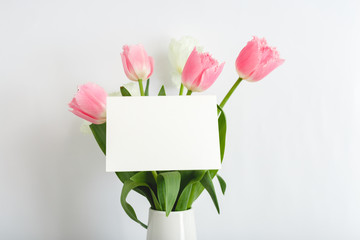 Flowers mock up congratulation. Congratulations card in bouquet of pink tulips on white background. White blank card with space for text, frame mockup. Spring festive flower concept, gift card.