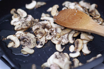 Adding ground black pepper into skillet with fried champignon mushroom