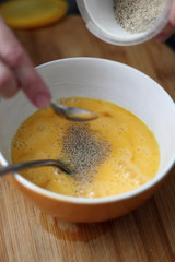 Adding white ground pepper into beaten eggs in bowl. Making omelette series.