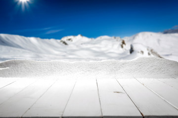 White wooden desk cover of white snow and free space for your decoration.Mountains in Alps and sunny cold day. 