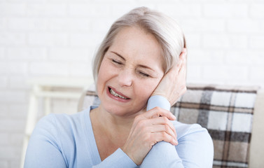 Tinnitus. Closeup up side profile sick female having ear pain touching her painful head.